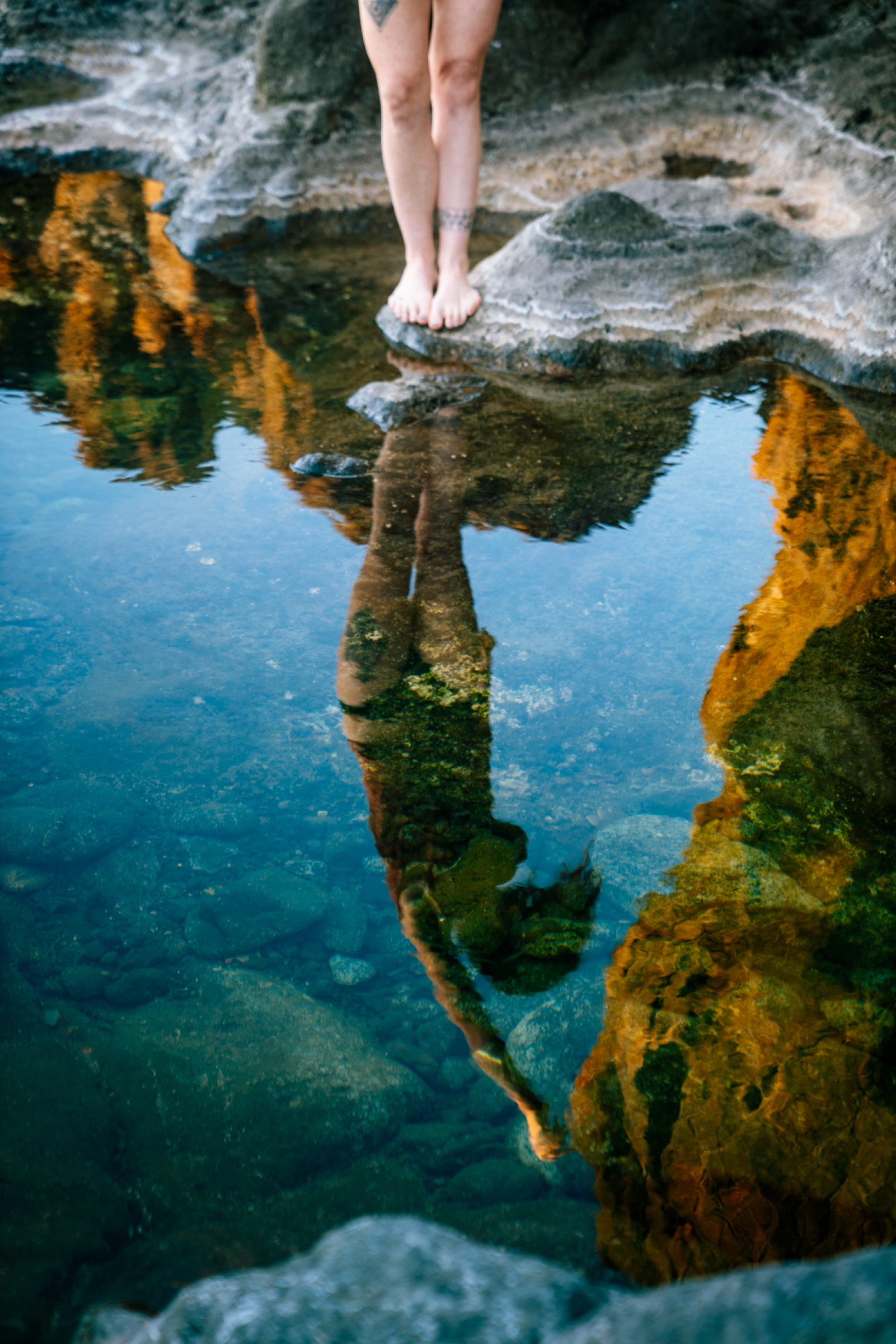 Reflection of Natalie Bruce in a still tide pool among volcanic rock in Tenerife