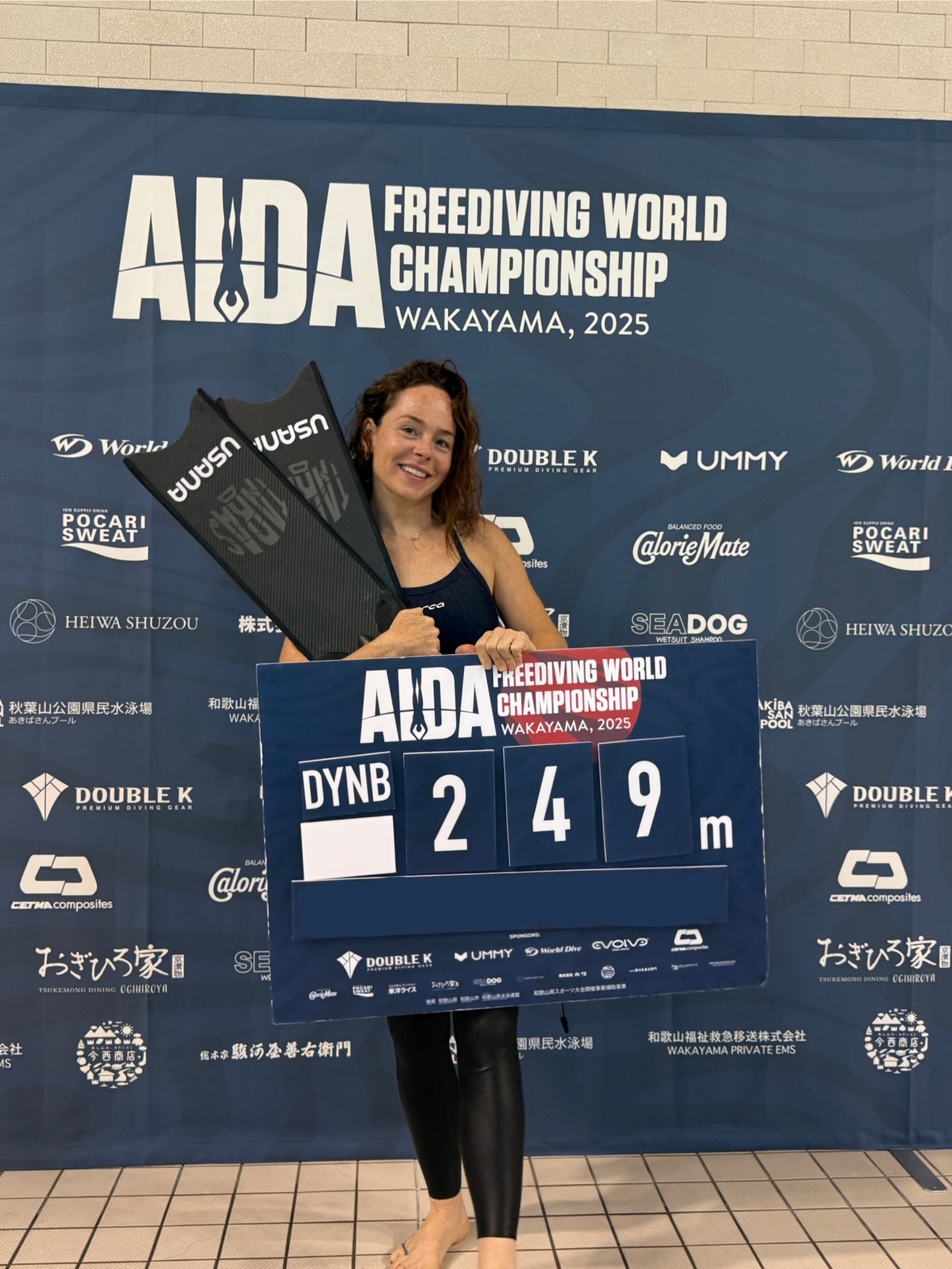 Natalie Bruce holding the 249 m result board at the 2025 AIDA World Championships in Wakayama, Japan