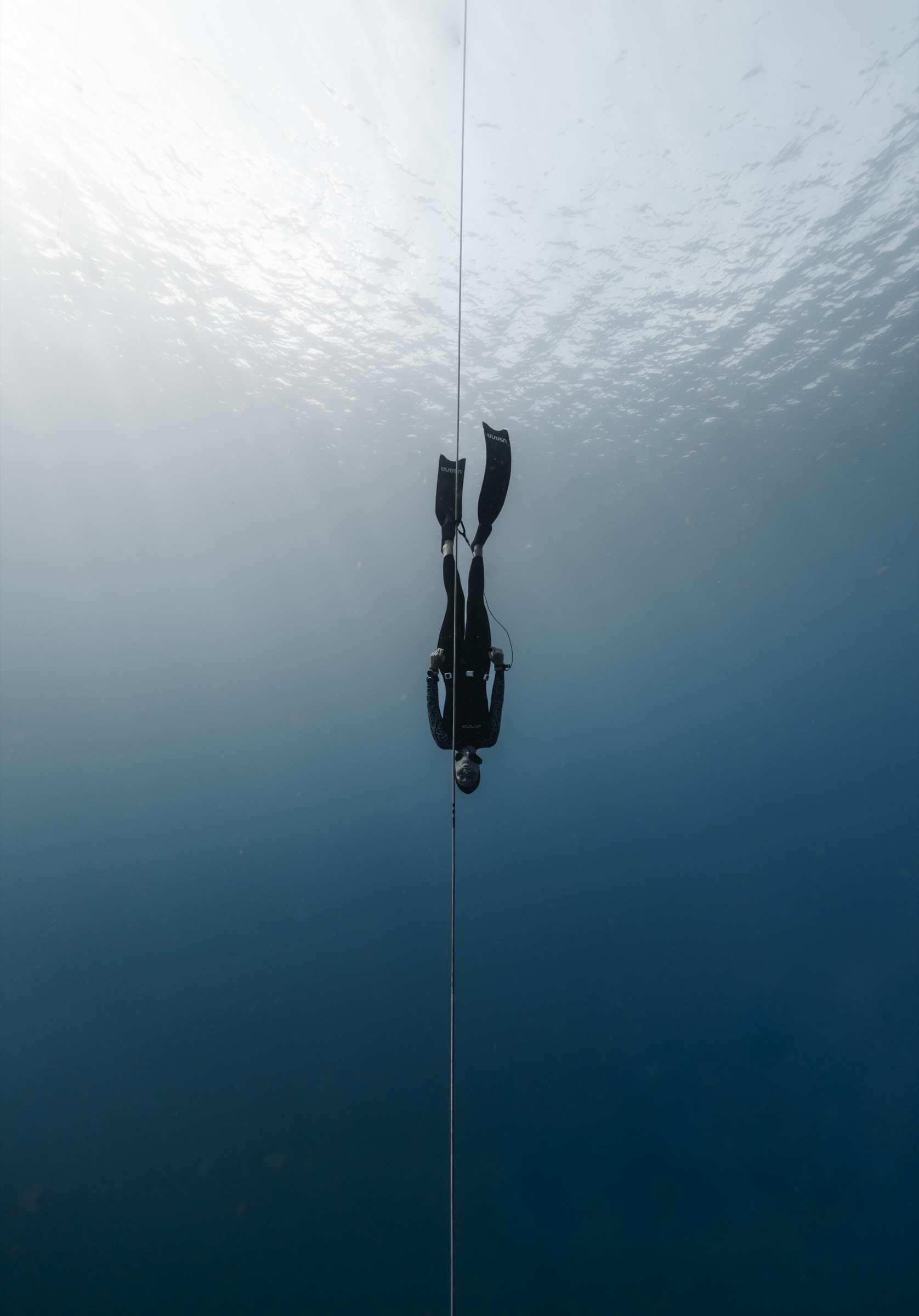 Natalie Bruce freediving on a deep descent with light rays, Tenerife