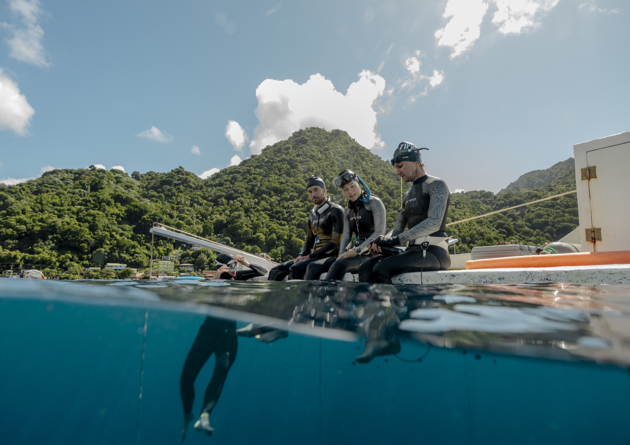 Freedivers sitting on the edge of the dive boat in open water